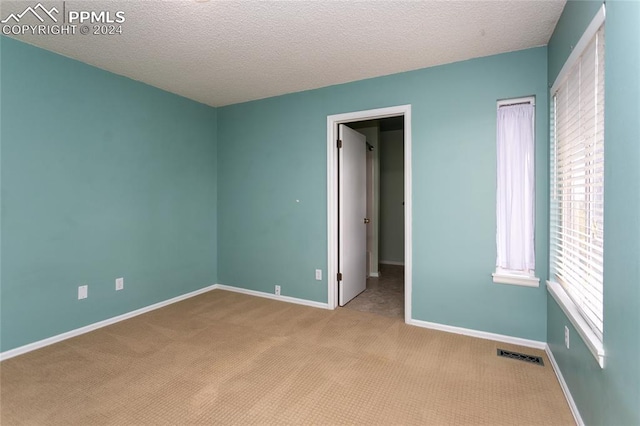 carpeted spare room featuring a textured ceiling