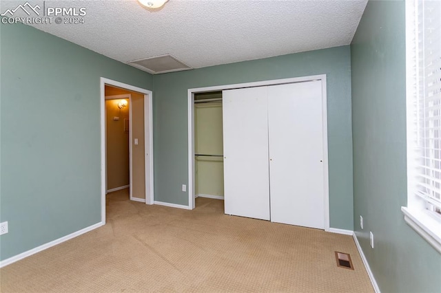 unfurnished bedroom with light carpet, a closet, and a textured ceiling