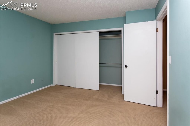 unfurnished bedroom with light carpet, a textured ceiling, and a closet