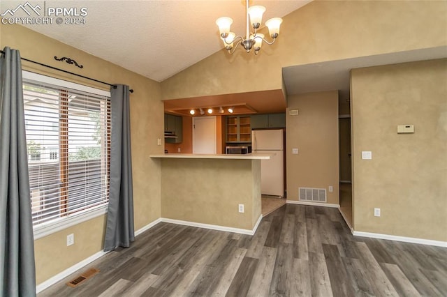 interior space featuring kitchen peninsula, a breakfast bar, a notable chandelier, white refrigerator, and dark hardwood / wood-style flooring