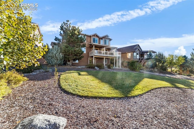 back of house with a balcony and a lawn