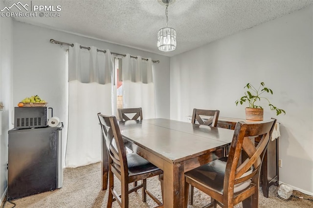 dining space featuring a textured ceiling, an inviting chandelier, and light colored carpet