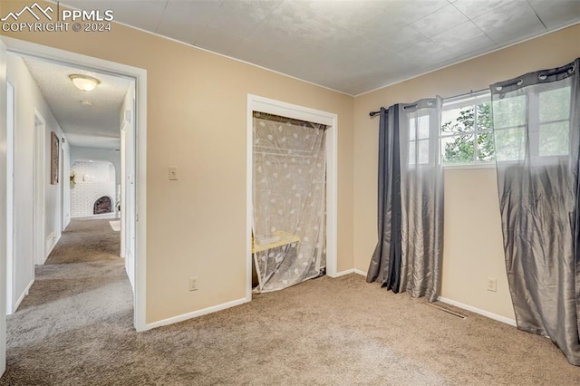 unfurnished bedroom with light carpet and a brick fireplace