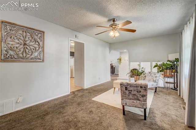 sitting room with carpet floors, a textured ceiling, and ceiling fan