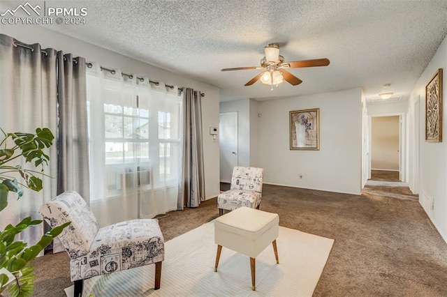 living area featuring ceiling fan, carpet flooring, and a textured ceiling