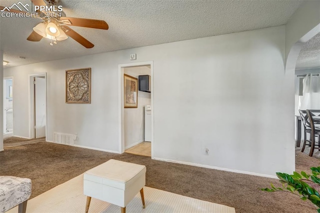 carpeted living room featuring a textured ceiling and ceiling fan