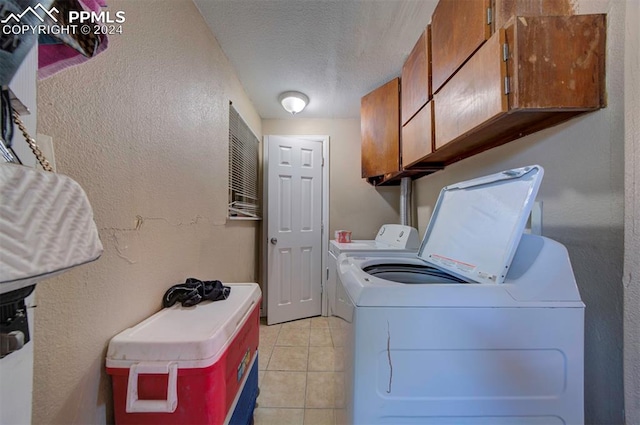 laundry area featuring washer and dryer, a textured ceiling, cabinets, and light tile patterned floors