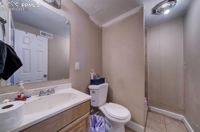 bathroom featuring toilet, vanity, a shower, and tile patterned floors