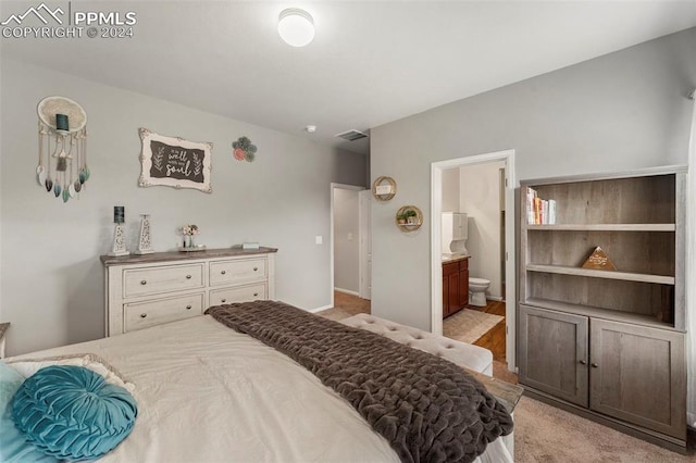 bedroom featuring ensuite bath and light colored carpet