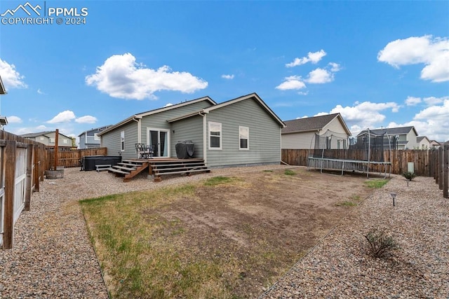 back of property with a wooden deck and a trampoline