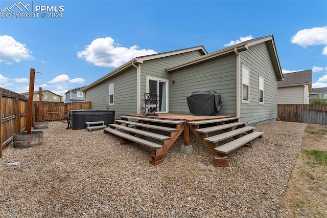 back of property featuring a wooden deck and a hot tub