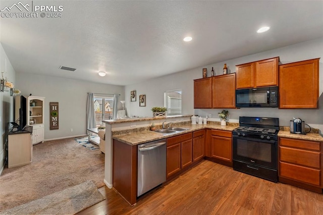 kitchen featuring light hardwood / wood-style floors, kitchen peninsula, black appliances, and sink