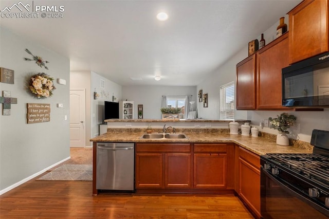 kitchen featuring stone counters, black appliances, sink, kitchen peninsula, and light hardwood / wood-style floors