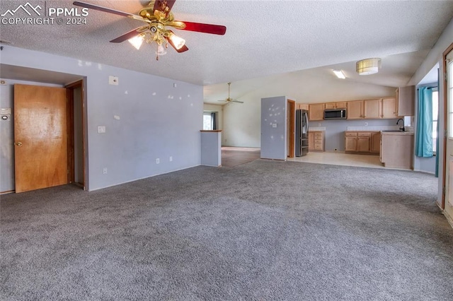 unfurnished living room featuring light carpet, sink, vaulted ceiling, ceiling fan, and a textured ceiling