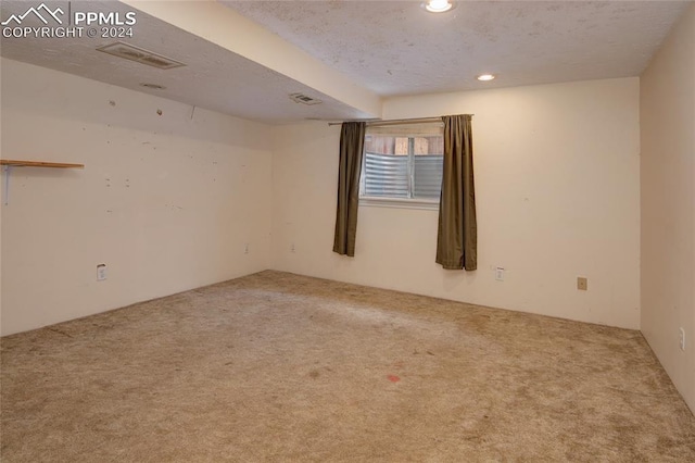 spare room featuring carpet flooring and a textured ceiling