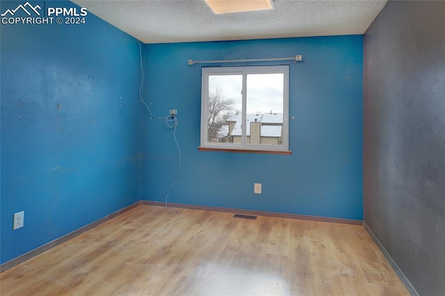 unfurnished room featuring light wood-type flooring and a textured ceiling