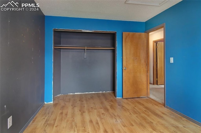 unfurnished bedroom with a closet, light hardwood / wood-style flooring, and a textured ceiling