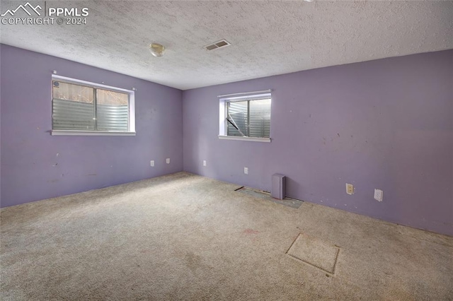 carpeted spare room with a textured ceiling