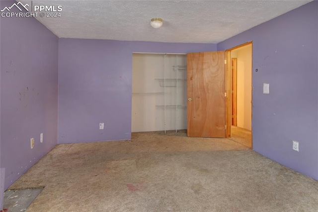 carpeted empty room with a textured ceiling