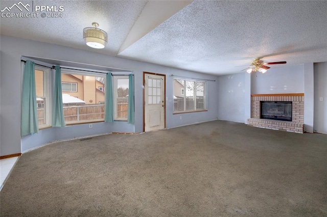 unfurnished living room featuring ceiling fan, a fireplace, carpet, and a textured ceiling