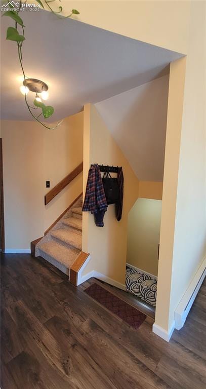 staircase with wood-type flooring and lofted ceiling