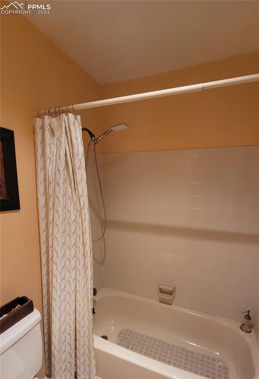 bathroom with shower / bath combo with shower curtain and toilet