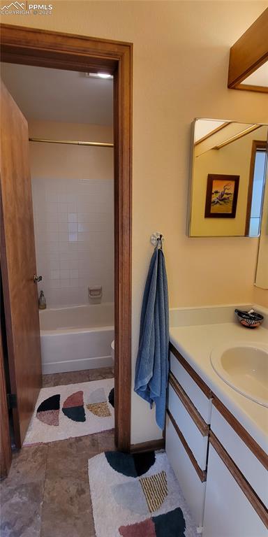 bathroom with tiled shower / bath combo and vanity