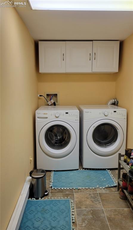 clothes washing area with washing machine and dryer and cabinets