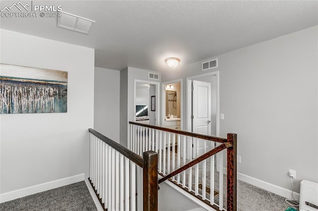 hallway featuring a textured ceiling and carpet flooring