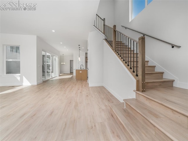 9568 Wolf Valley Dr, Colorado Springs, CO 80924 - unfurnished living room featuring stairs, light wood-type flooring, baseboards, and recessed lighting