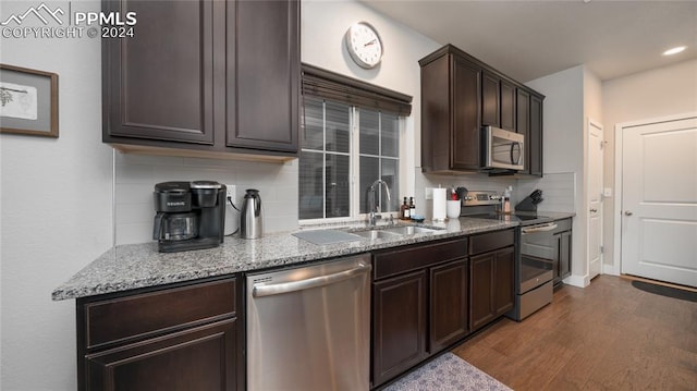 kitchen featuring dark wood-type flooring, stainless steel appliances, decorative backsplash, and sink