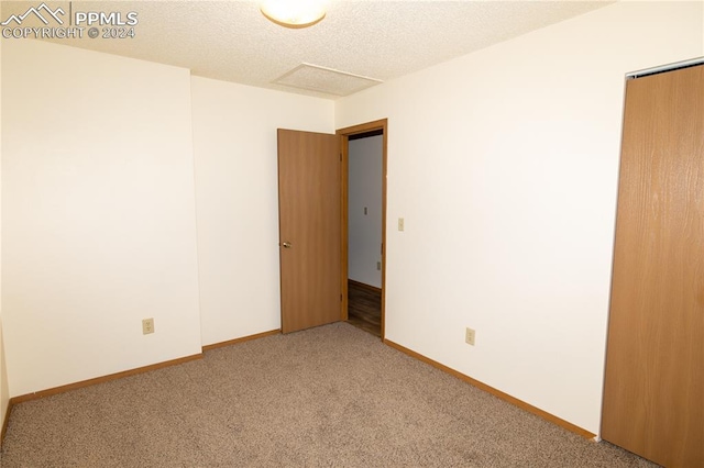 carpeted empty room with a textured ceiling