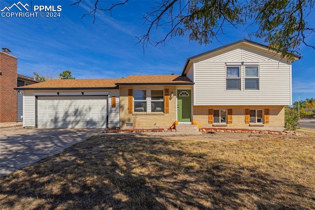 tri-level home featuring a front lawn and a garage