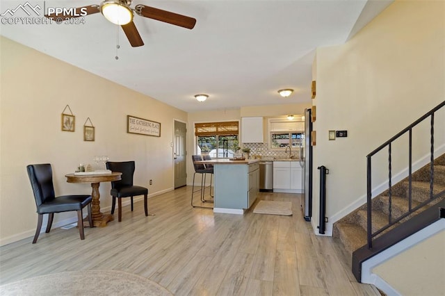 kitchen featuring white cabinets, tasteful backsplash, a breakfast bar, light wood-type flooring, and stainless steel appliances