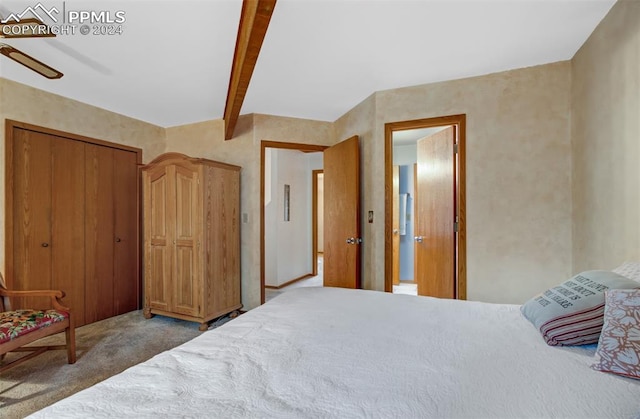 carpeted bedroom with a closet and beamed ceiling