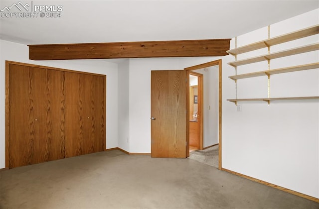 spare room featuring light carpet and beamed ceiling