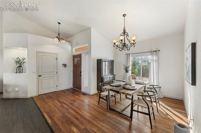 dining area with an inviting chandelier, hardwood / wood-style floors, and vaulted ceiling