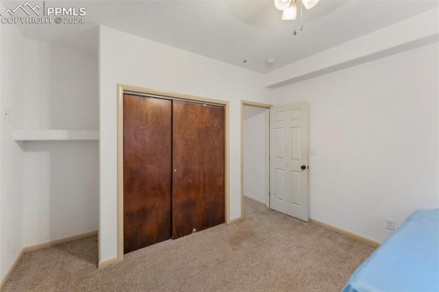 unfurnished bedroom featuring a closet, ceiling fan, and light colored carpet