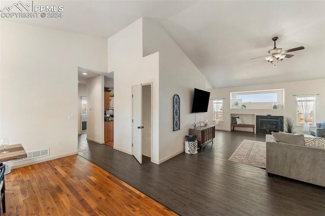 living room featuring ceiling fan, high vaulted ceiling, a wood stove, and dark hardwood / wood-style floors