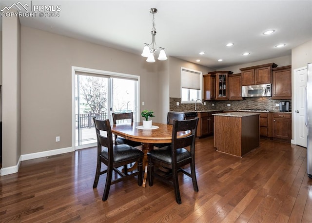 dining area featuring sink, dark wood-type flooring, and a notable chandelier