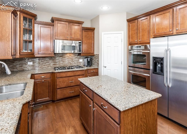 kitchen featuring dark hardwood / wood-style floors, light stone counters, sink, and appliances with stainless steel finishes