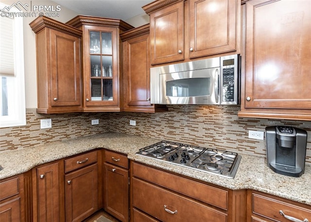 kitchen featuring decorative backsplash, light stone counters, and appliances with stainless steel finishes