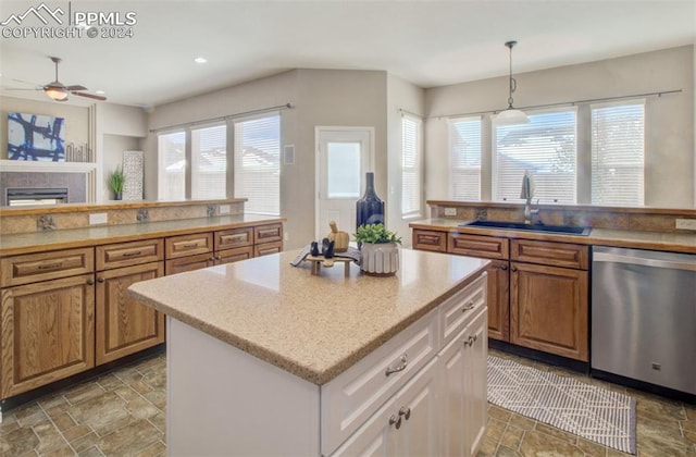 kitchen with white cabinetry, sink, decorative light fixtures, stainless steel dishwasher, and a kitchen island