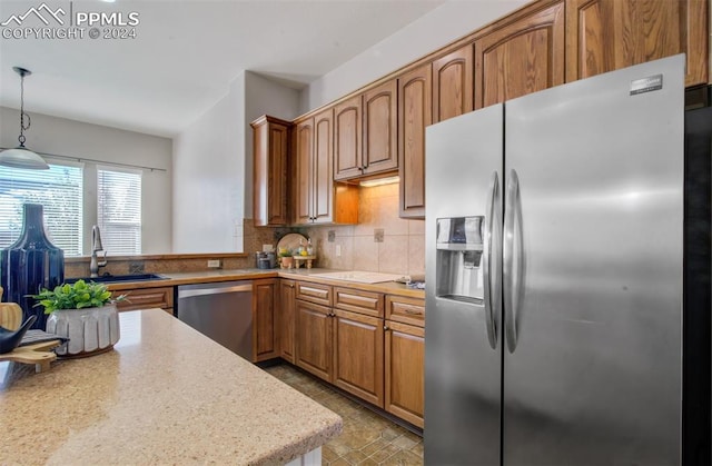 kitchen featuring stainless steel appliances, hanging light fixtures, sink, and tasteful backsplash