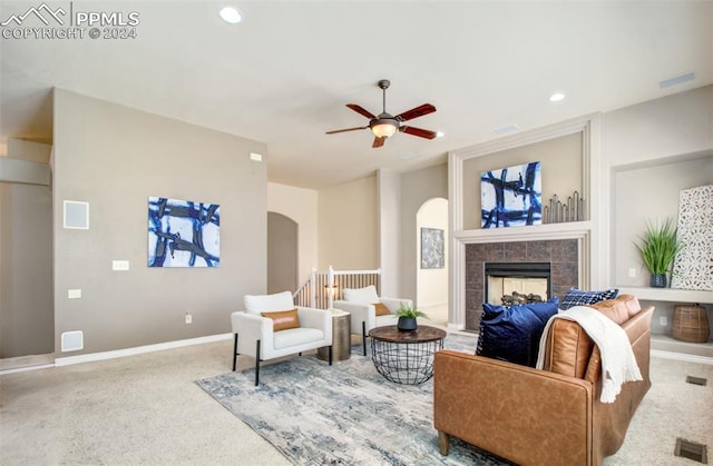 living room featuring ceiling fan and a tile fireplace