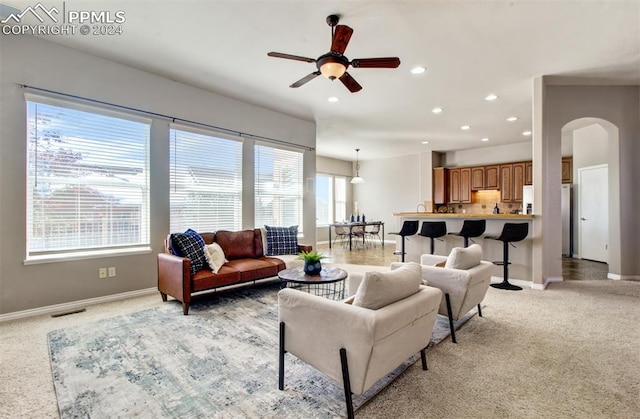 living room with ceiling fan, light carpet, and a healthy amount of sunlight