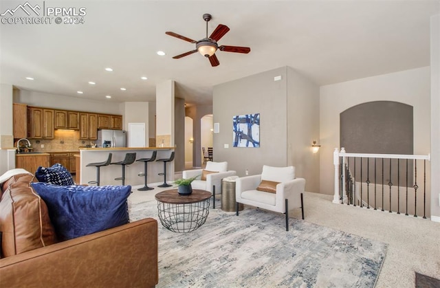 carpeted living room featuring sink and ceiling fan