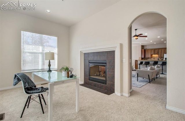 carpeted office with a tiled fireplace and ceiling fan