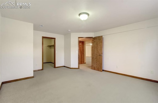 unfurnished bedroom with light colored carpet, a closet, and a walk in closet