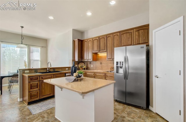 kitchen with sink, kitchen peninsula, stainless steel refrigerator with ice dispenser, hanging light fixtures, and a center island